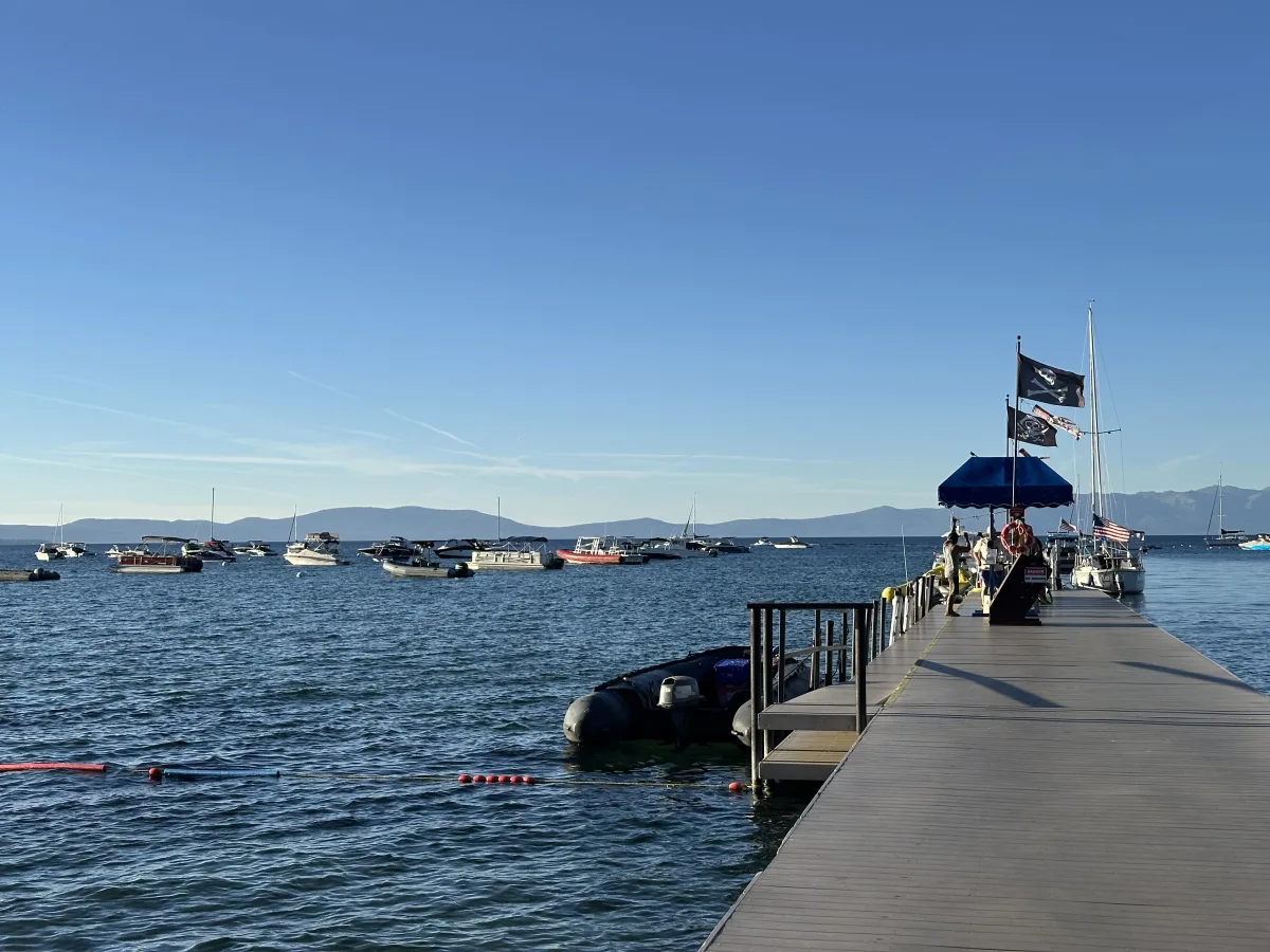 Wide waterfront scene with a long dock extending from the lower-right into a lake/sea.