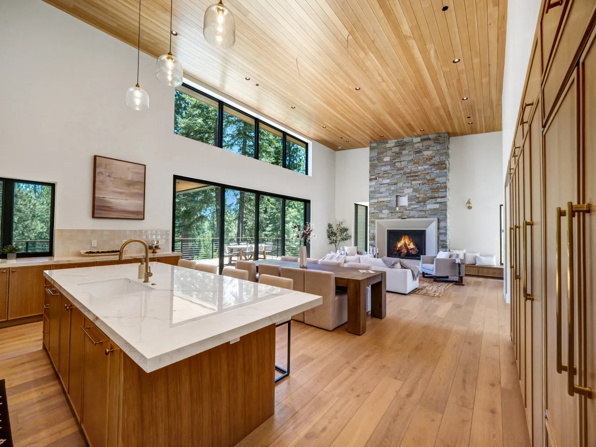 Bright, modern open-plan interior combining a kitchen island in the foreground with a dining table and living area in the background.